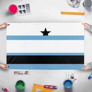 A mockup of the custom flag 'T flag' held up on a table during print checking