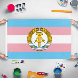 A mockup of the custom flag 'Trans German Democratic Republic flag' held up on a table during print checking