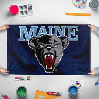 A mockup of the custom flag 'UMaine Flag' held up on a table during print checking